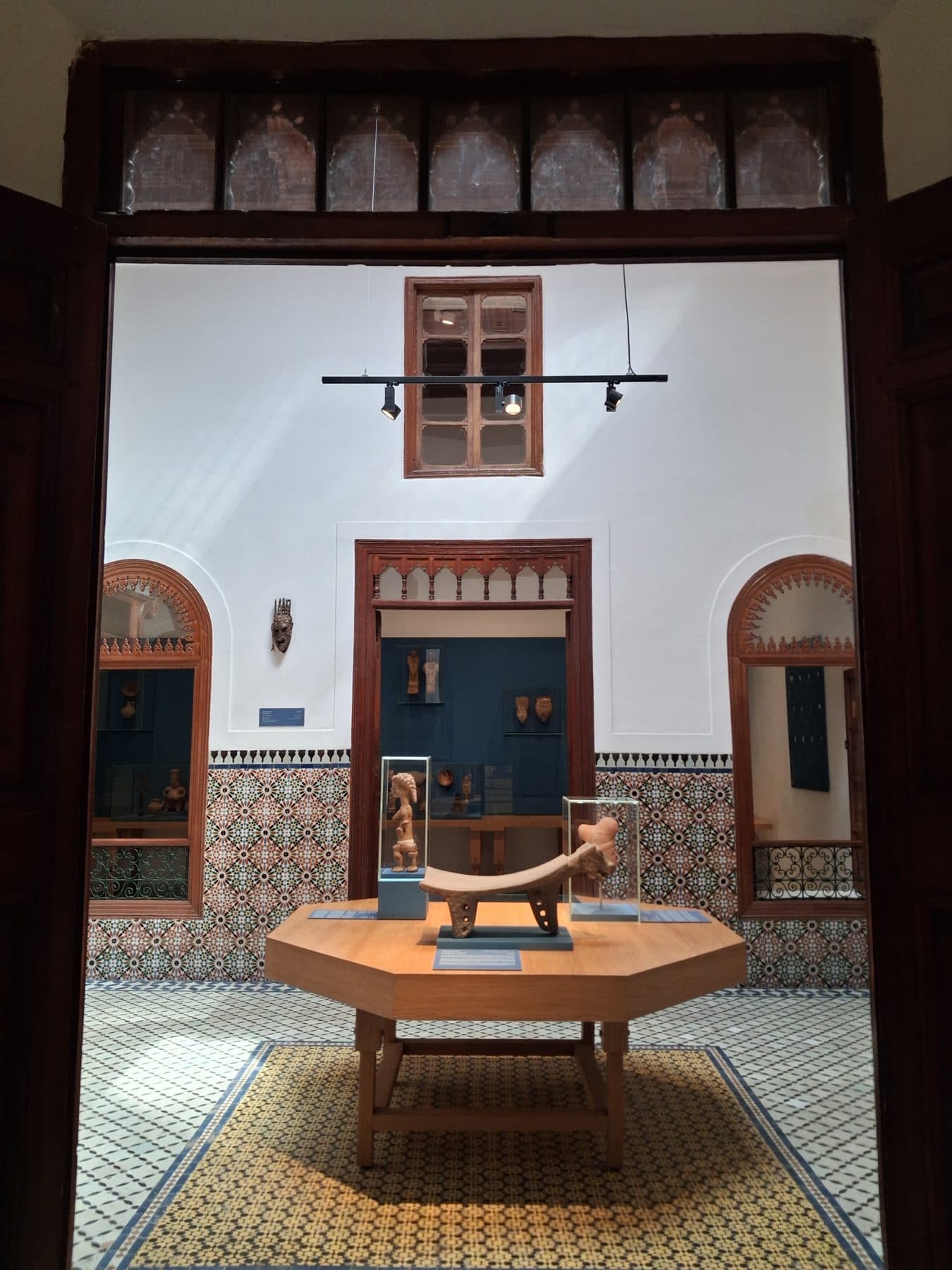 Salle d'exposition ouverte sur la cour, avec des objets en vitrine et sur une table octogonale, Dar El Bacha