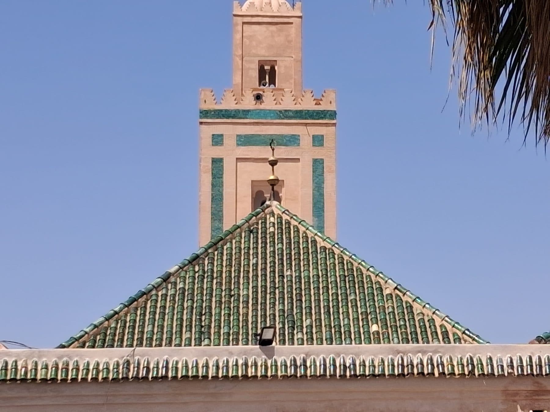 Minaret à bandeaux de zellige et toit de tuiles vertes, près de la qoubba almoravide