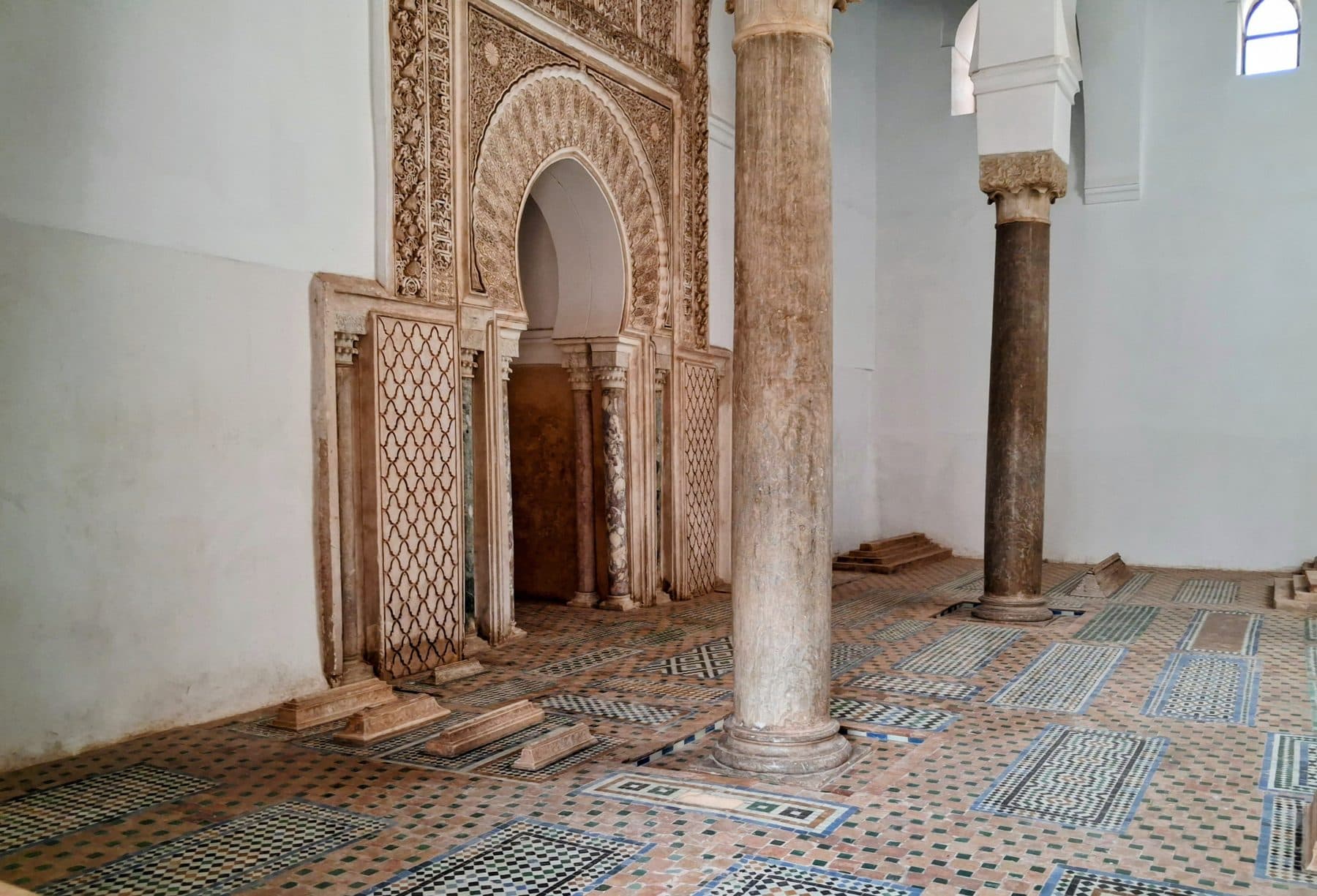 Salle des tombeaux saadiens avec un mihrab en stuc sculpté, des colonnes de marbre et un sol de tombes en zellige