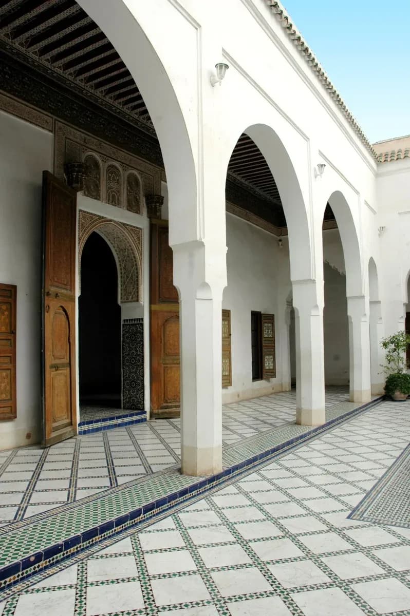 Galerie à arcades blanches et sol en zellige autour de la cour du riad de Dar Bellarj
