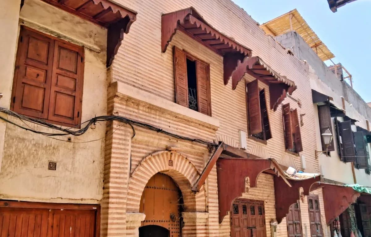 Façades à balcons couverts et fenêtres en bois dans une rue du Mellah de Marrakech