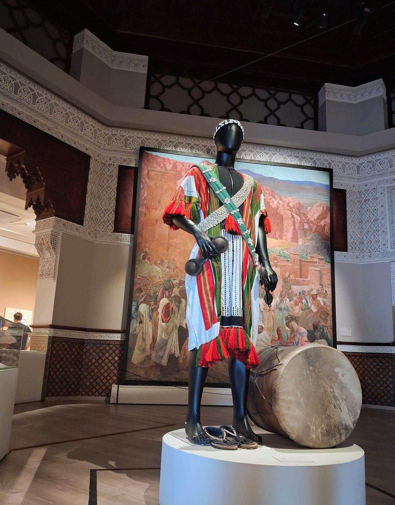 Costume de musicien et grand tambour exposés au musée Jemaa el-Fna, devant une peinture de cérémonie